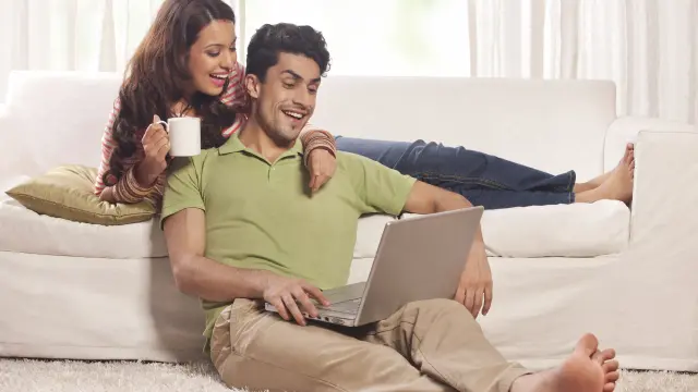 A couple is comfortably lying on their couch in her house with Bosch Smart Hime technology.